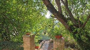 Un sendero que atraviesa un jardín con pilares de ladrillo y plantas en macetas.
