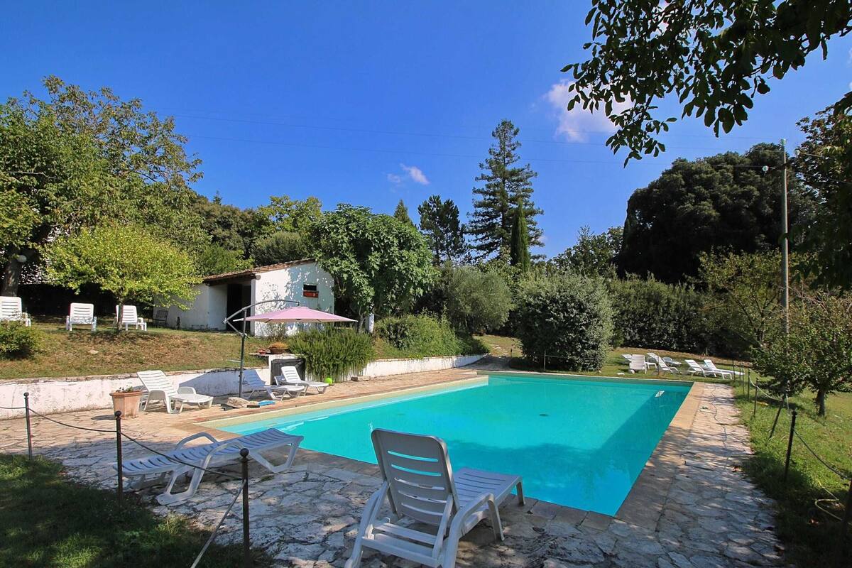A swimming pool with white lounge chairs and a stone patio.