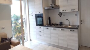 A modern kitchen with white cabinetry, a built-in oven, a gas stove, and a stainless steel sink. - Apartment Baricevic (Opatija)