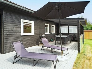 Een terras met twee ligstoelen, een tafel en een parasol.