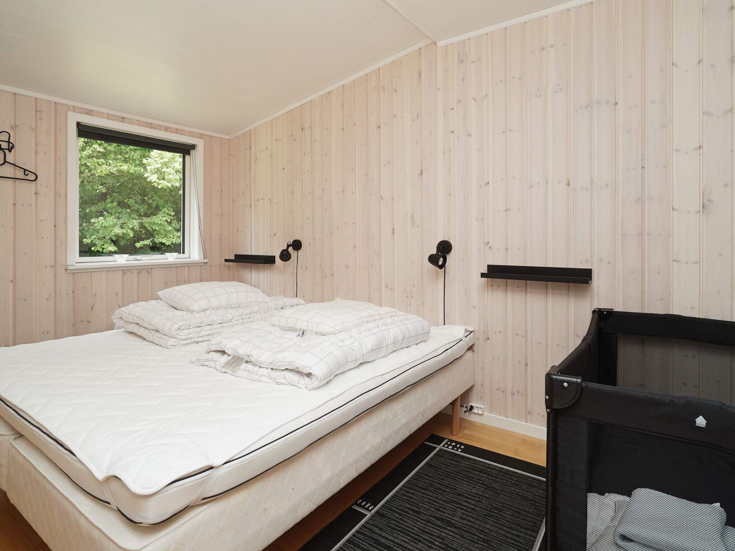 A bedroom with a bed, a window, and a black headboard.