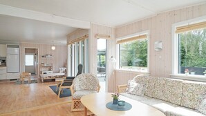 A modern interior with a wooden floor, a sofa, a dining table, and a kitchen area. - 6 Person Holiday Home in Hojby (Hojby)