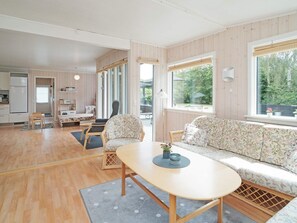 A modern interior with a wooden floor, a sofa, a dining table, and a kitchen area. - 6 Person Holiday Home in Hojby (Hojby)