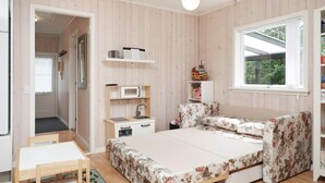 A bedroom with a bed, a desk, a chair, a small kitchenette, and a window. - 6 Person Holiday Home in Hojby (Hojby)