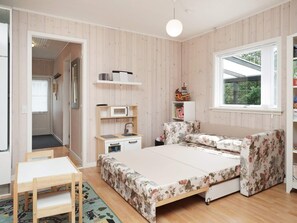 A bedroom with a bed, a desk, a chair, a small kitchenette, and a window. - 6 Person Holiday Home in Hojby (Hojby)