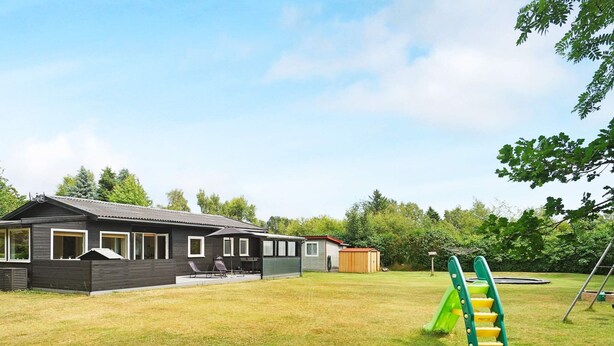 A residential property with a house, a patio with outdoor furniture, and a playground with a slide. - 6 Person Holiday Home in Hojby (Hojby)