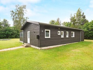 A single-story building with a dark exterior, a door, and four windows. - 6 Person Holiday Home in Hojby (Hojby)