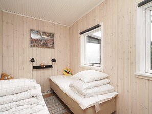 A bedroom with two beds, a window with blinds, a painting on the wall, and a small shelf with a teddy bear. - 6 Person Holiday Home in Hojby (Hojby)