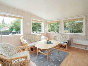 A cozy room with a round wooden table, two patterned sofas, and wicker chairs.