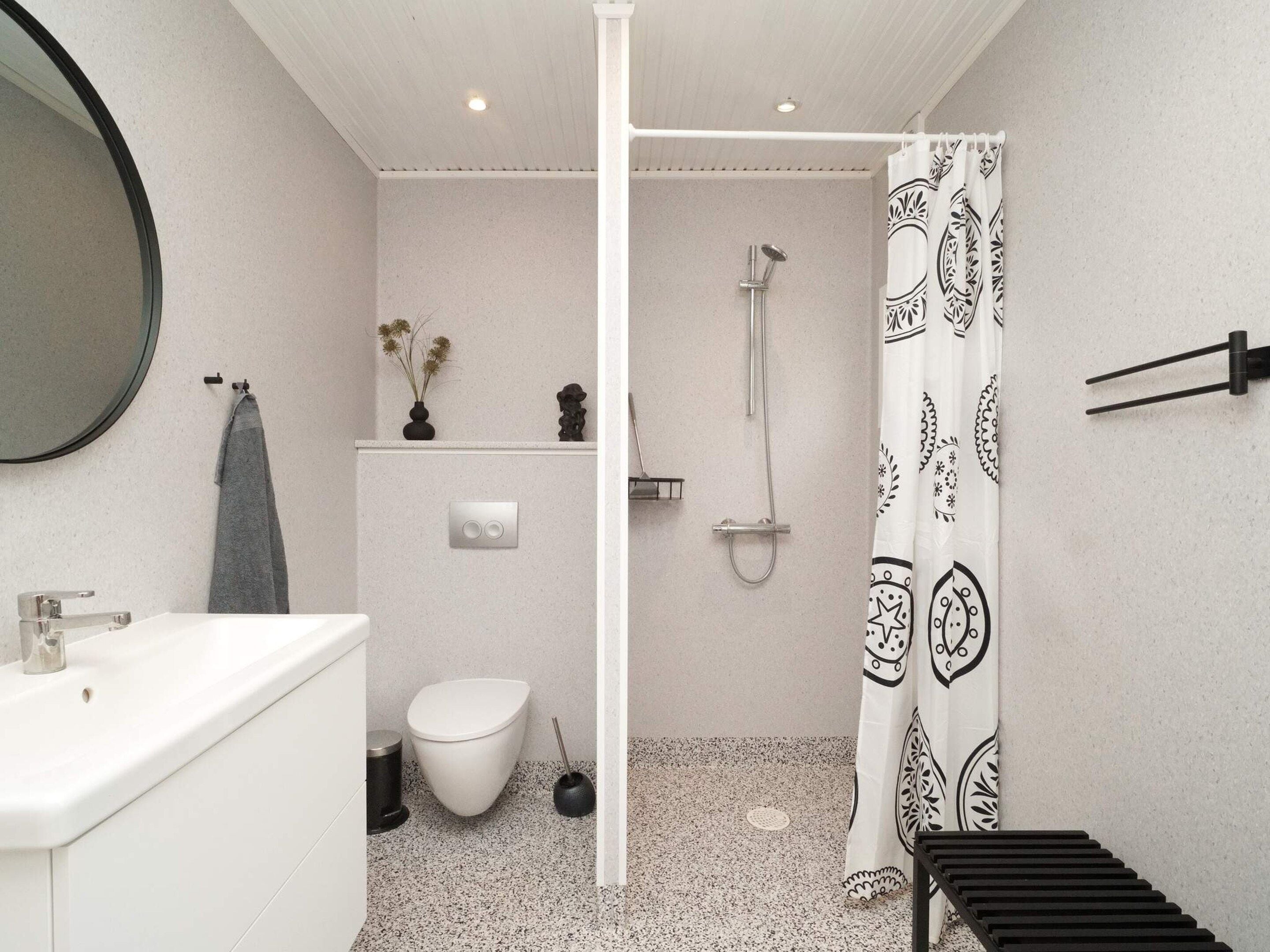 Ein modernes Badezimmer mit Waschbecken, Toilette und Duschbereich in Weiß.