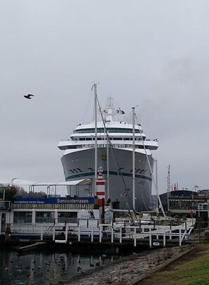 A large cruise ship docked at a port with a viewing platform and a sign that reads "Sonnenterrasse." - De Bohn Comfortable Holiday Residence (Lübeck)