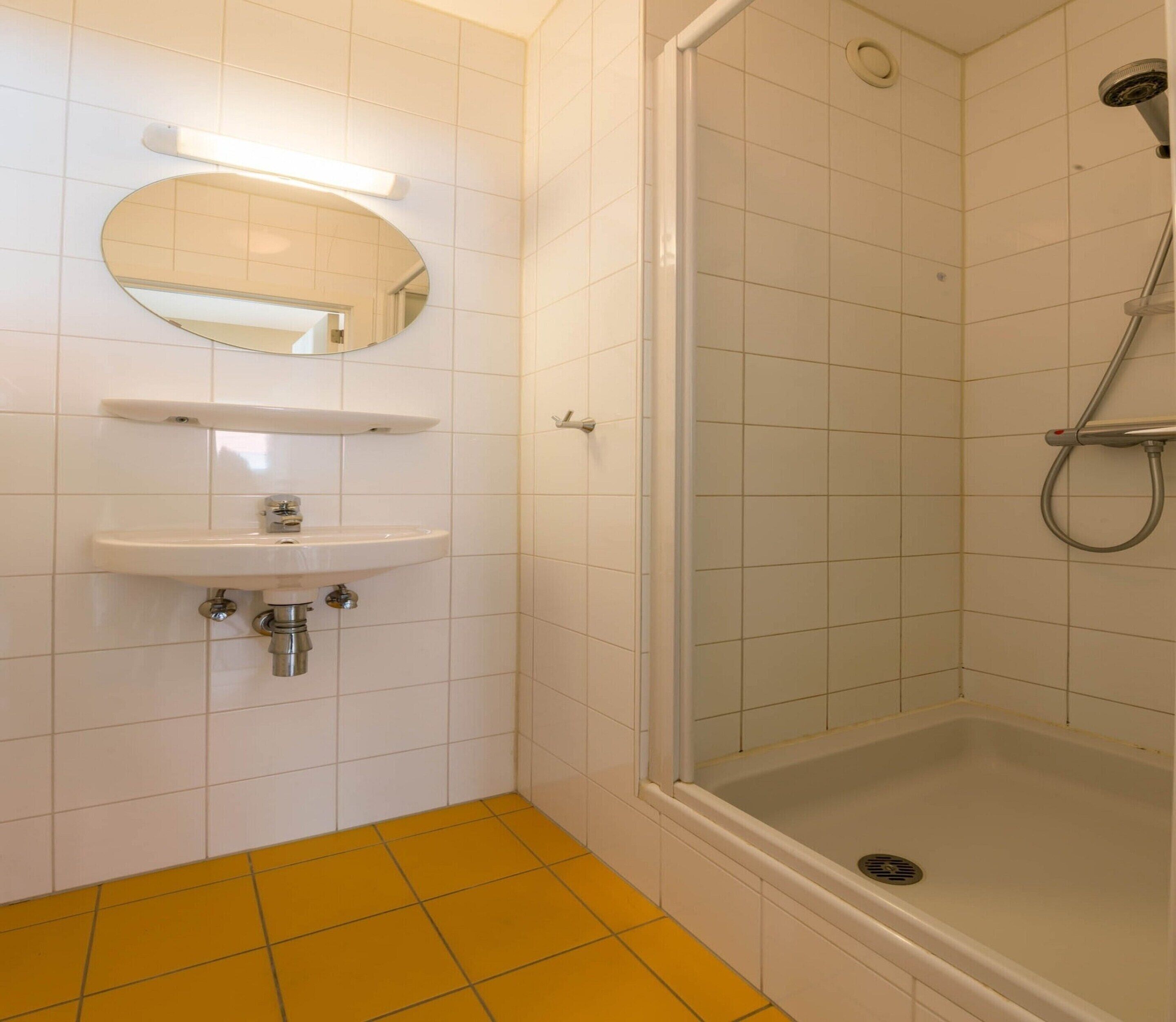 A bathroom with a white sink, mirror, and shower.
