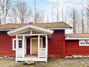 A red wooden house with a white porch and a yellow door. - 4 Person Holiday Home in Aseda (Åseda)