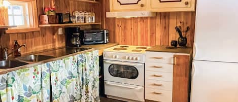 A compact kitchen with a stove, oven, microwave, and a refrigerator.