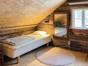 A small, cozy room with a single bed, a round rug, and a window with a view of the outside.