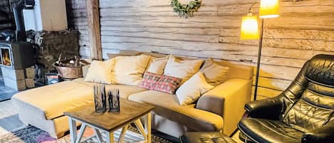 Un salón acogedor con un sofá, un sillón de cuero, una mesa de centro y una chimenea.