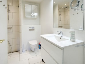 A modern bathroom with a white sink, a toilet, a shower, and a large mirror. - 6 Person Holiday Home in Gilleleje (Gilleleje)
