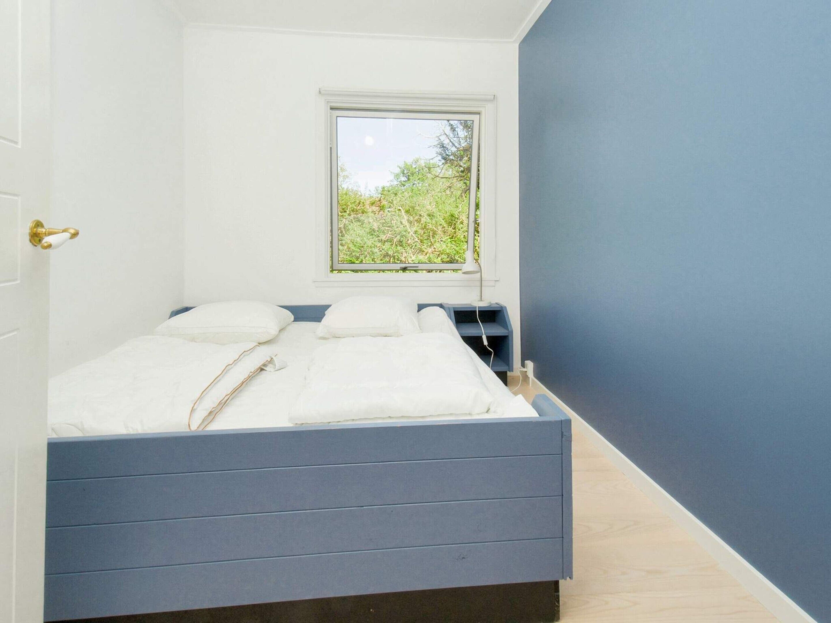 Un dormitorio con cama, ventana y mesita de noche.