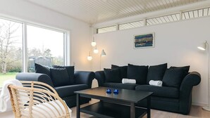 A modern living room with a dark grey sofa, a wooden chair, and a coffee table. - 6 Person Holiday Home in Gilleleje (Gilleleje)