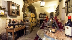 Une cave à vin avec des barriques en bois, des bouteilles de vin et une vitrine exposant des verres à vin et des bouchons.
