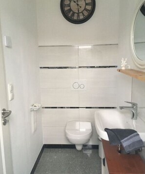 Een kleine badkamer met toilet, bidet en een wastafel met handdoek.