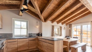 Eine moderne Küche mit Holzschränken, einer großen Kochinsel und Blick ins Freie.
