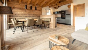 Eine moderne Küche mit Edelstahlgeräten, einer Holzbalkendecke und einem Essbereich mit Tisch und Stühlen.