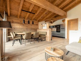 Cozinha moderna com eletrodomésticos de aço inoxidável, teto de madeira e área de refeições com mesa e cadeiras.