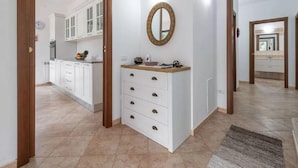 Un pasillo con una zona de cocina, un espejo y un armario blanco con cajones.