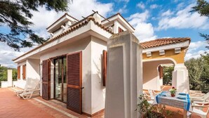 Una casa de dos pisos con un patio, una puerta corrediza de vidrio y una mesa lista para comer.