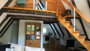 A loft-style room with exposed wooden beams, a dining area, and a kitchen. - \"the Elf\" Comfortable Holiday Residence (Gartow)