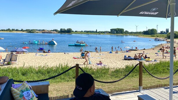 A beach with a wooden deck, lounge chairs, and umbrellas. - Apartment With Sauna and Terrace in Gelderland (Lathum)