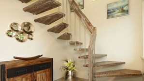 Eine Holztreppe mit rustikalem Design, eine Holzkabine mit Schubladen und eine Vase mit Blumen.