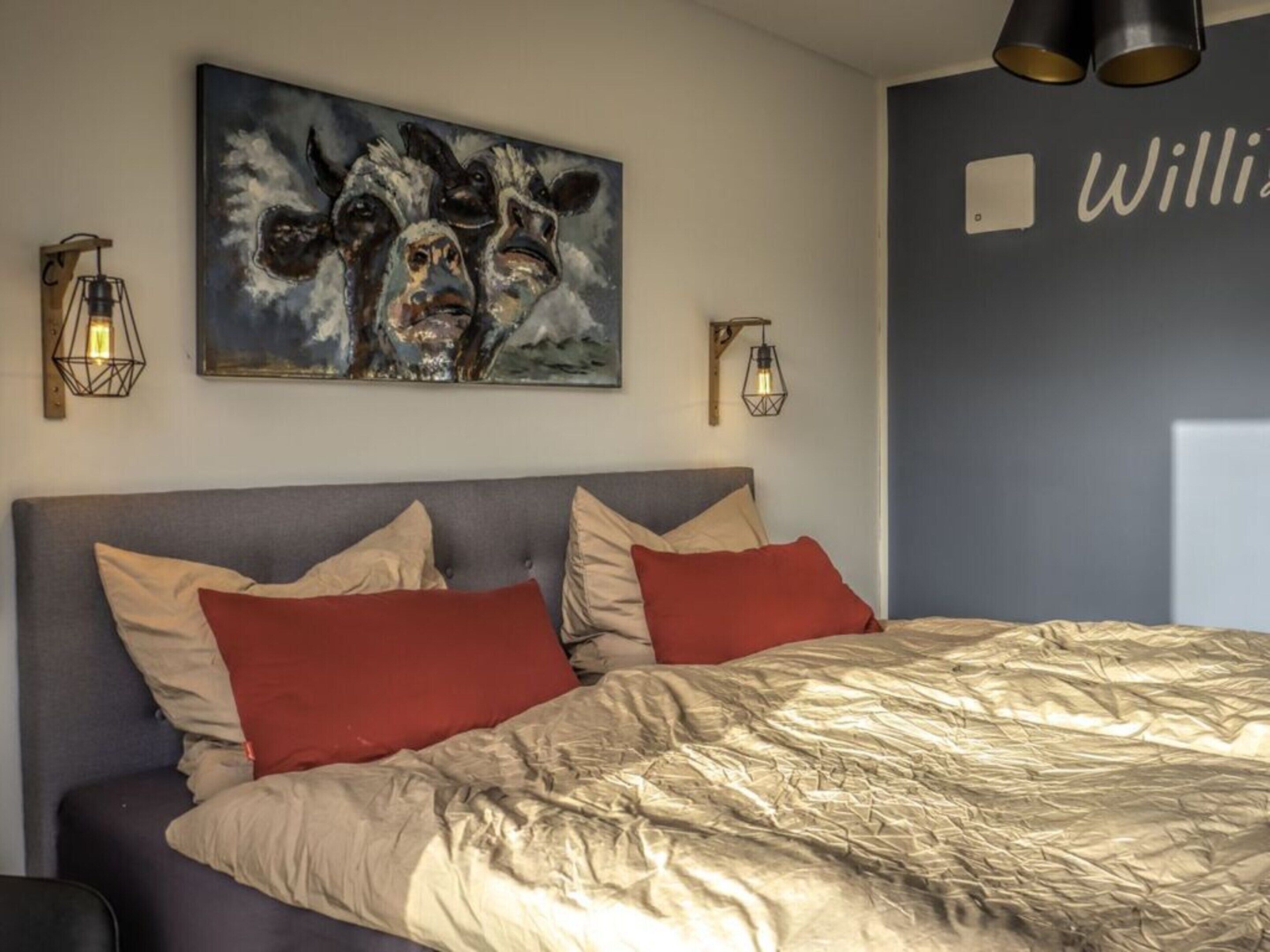 Un dormitorio con una cama, dos lámparas de pared y un cuadro sobre la cama.