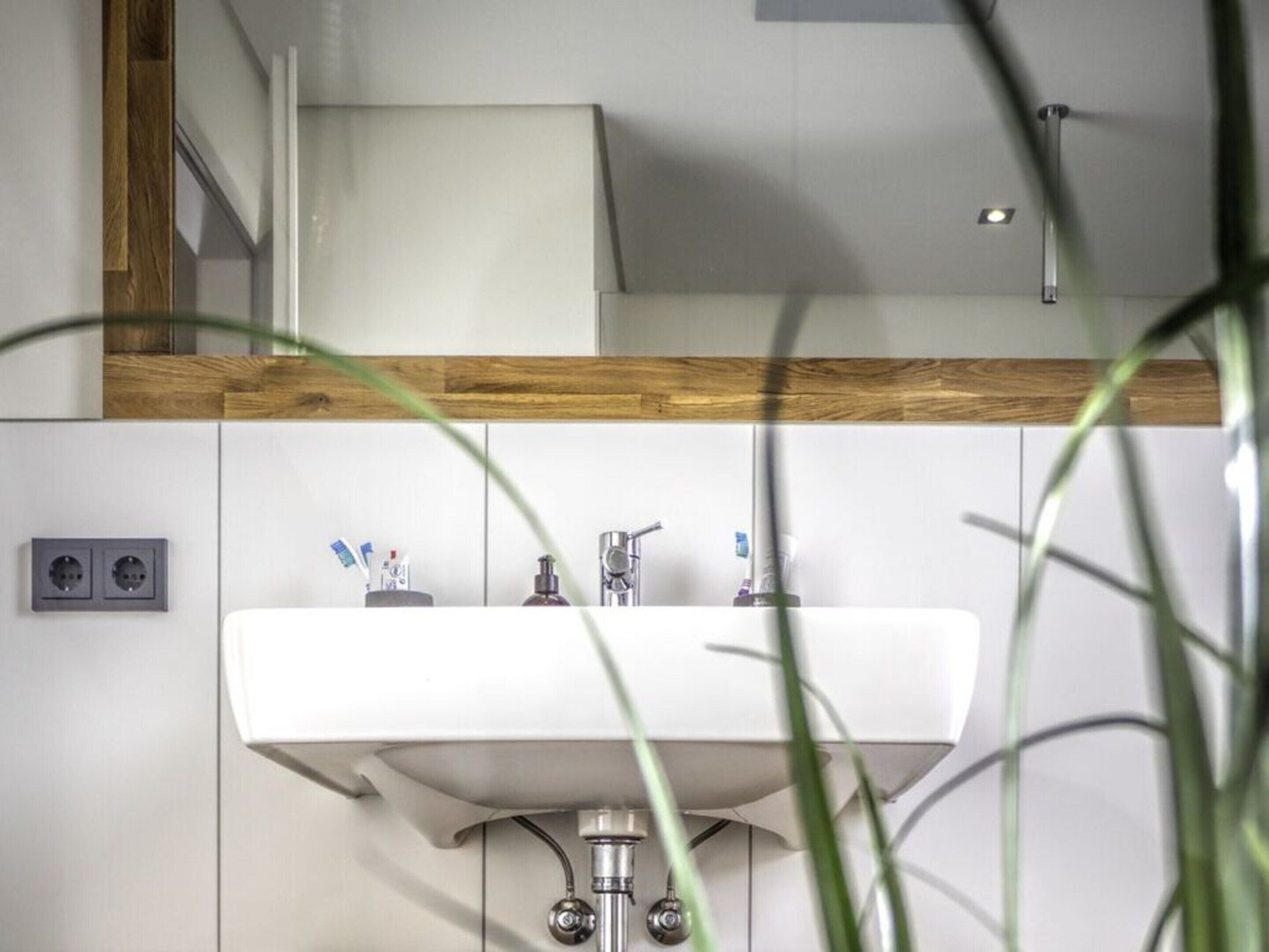 Un baño moderno con un lavabo blanco, paneles de madera y un espejo encima.