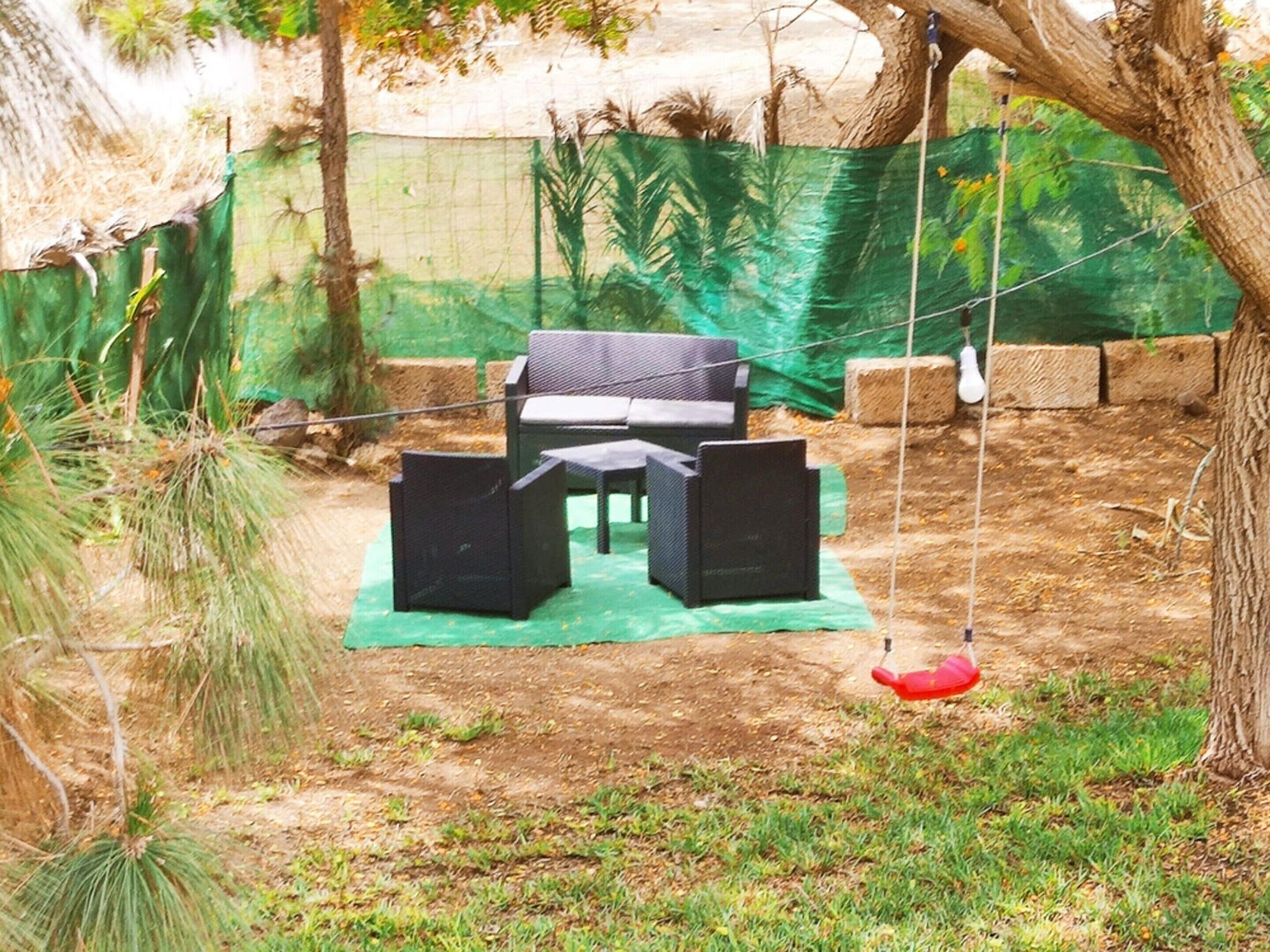 A patio area with a swing set, a table, and chairs.