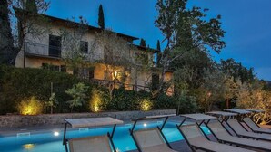 A swimming pool with lounge chairs and a stone wall. - Villa Montecchio Comfortable Holiday Residence (Cortona)