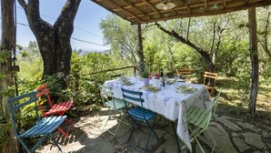 An outdoor dining area with a table set for two, surrounded by chairs and a wooden pergola overhead. - Villa Montecchio Comfortable Holiday Residence (Cortona)