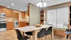 A compact kitchen with wooden cabinets, a built-in oven, and a dining area with a table and chairs.