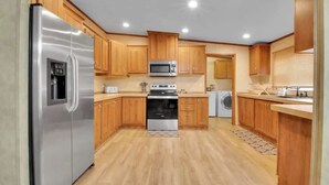 A modern kitchen with wooden cabinets, stainless steel appliances, a microwave, oven, and a washing machine.