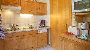A compact kitchen with wooden cabinets, a microwave, a coffee maker, and a toaster. - Holiday Apartment Tannenblick (Hinterzarten)