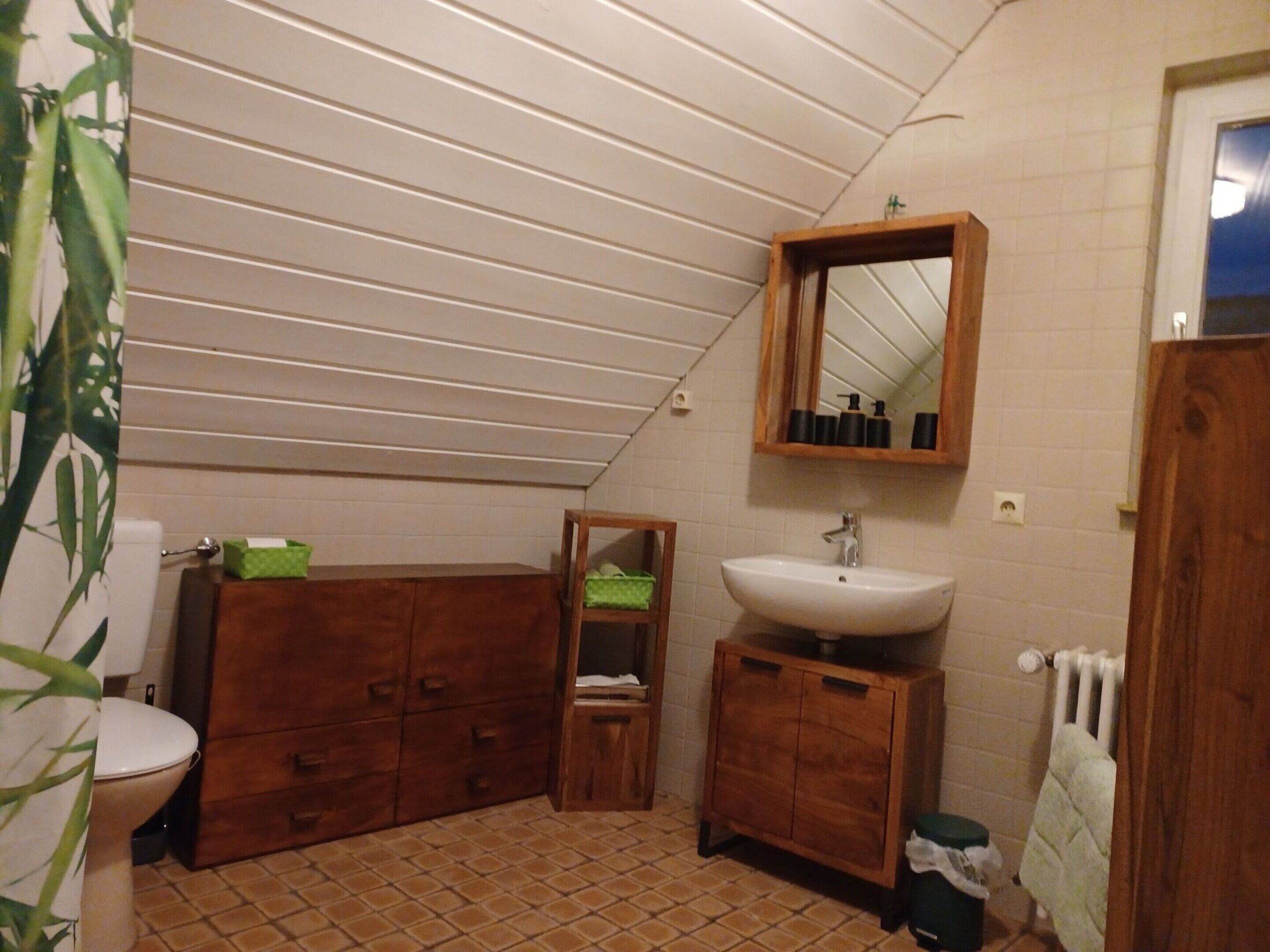 Un baño pequeño con inodoro, armarios de madera, un lavamanos y un espejo.