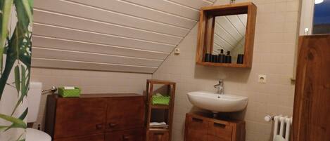 Un baño pequeño con inodoro, armarios de madera, un lavamanos y un espejo.