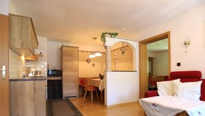 Ett kompakt bostadsutrymme med ett kök, en matplats och en röd soffa.