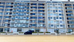 A multi-story residential building with balconies, large windows, and a parking area with a car. - Nieuwpoort Central Retreat (Nieuwpoort)