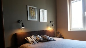 A neatly made bed with patterned pillows, two wall-mounted reading lamps, and framed artwork above it. - Apartments Villa Dona -two Bedroom Apartment With Shared Swimming Pool (Vela Luka)