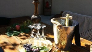 A wooden table with a metal bucket containing a bottle, a plate with grapes, and a candle. - Apartments Villa Dona -two Bedroom Apartment With Shared Swimming Pool (Vela Luka)