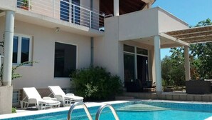 A modern two-story house with a swimming pool, outdoor seating, and a covered patio area. - Apartments Villa Dona -two Bedroom Apartment With Shared Swimming Pool (Vela Luka)