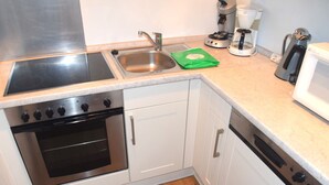 A compact kitchen with a stainless steel sink, a coffee maker, and a microwave. - Ferienhaus im Malerischen Allgau (Fuessen)