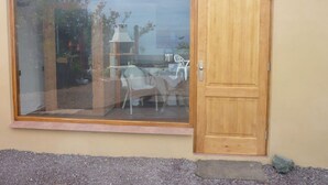A sliding glass door leading to a patio with a table and chairs, a small outdoor grill, and a view of the sky. - Holiday Home Finca (Icod de los Vinos)
